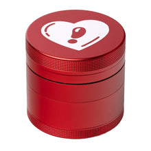 The BIGFUN! Medium Grinder is a red aluminum grinder with a textured grip and a white heart with an exclamation mark on the lid, combining style and practicality.