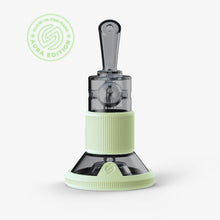 The SOFTGLASS AURA TANDEM RIG is a modern smoking device with transparent and pale green glow-in-the-dark accents, silicone sleeves on its cylindrical mouthpiece and ribbed base, plus a “Glow-in-the-Dark Aura Edition” badge at the top left.