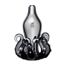 The Octopus Carb Cap is a transparent borosilicate glass accessory with curved, tentacle-like black details at the base and a narrow neck, featuring a small emblem—ideal for fans of unique dab accessories.