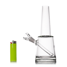 The MJ Arsenal Summit Bong, made of clear borosilicate glass with an angled mouthpiece and bowl, is shown next to a bright green lighter on a white background, highlighting its impressive water filtration.