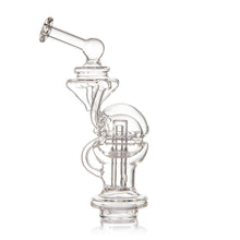 The MJ Arsenal Fabcycler Focus V Carta Top is a clear borosilicate glass water pipe with intricate curved and angular shapes, a sphere-like chamber, and a wide stable base, shown on a plain white background.