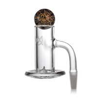 The MJ Arsenal Full Weld Quartz Terp Blender is a clear glass accessory with a cylindrical chamber and round bowl, compatible with quartz banger setups or MJ Arsenal Mini Rigs, shown here containing dark material on a white background.