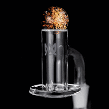 The MJ Arsenal Full Weld Quartz Terp Blender glows orange on its top surface when heated with a flame, emitting swirling sparks against a black background—ideal for use with MJ Arsenal Mini Rigs.