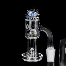 The MJ Arsenal Full Weld Quartz Terp Slurper is shown close-up with a spinning terp pearl and a blue-and-gold marble cap inside, set against a black background.