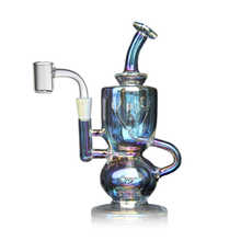 The MJ Arsenal Titan Mini Dab Rig, made from iridescent borosilicate glass, features a bent neck, side handle, and a clear quartz banger attachment, shown against a white background.