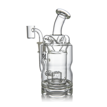 The MJ Arsenal Turbine Mini Dab Rig is a clear borosilicate glass water pipe with multiple chambers, a curved mouthpiece, and a side attachment for concentrates, standing upright on a white background.