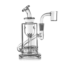 The MJ Arsenal Ursa Mini Dab Rig is a clear borosilicate glass rig with a cylindrical body, side arm, angled mouthpiece, black crown logo on the front, and quartz banger on the right. Shown against a white background.
