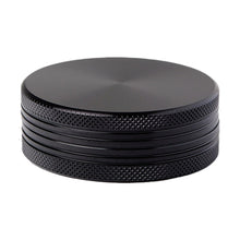 The 2 Piece Flat Grinder is a black, round metal grinder featuring a textured grip and a smooth, flat top, displayed on a white background.