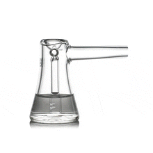 The MJ Arsenal Vulkan Bubbler is a clear borosilicate glass piece shaped like an Erlenmeyer flask that tips to pour liquid out its spout, then returns upright with less liquid inside.