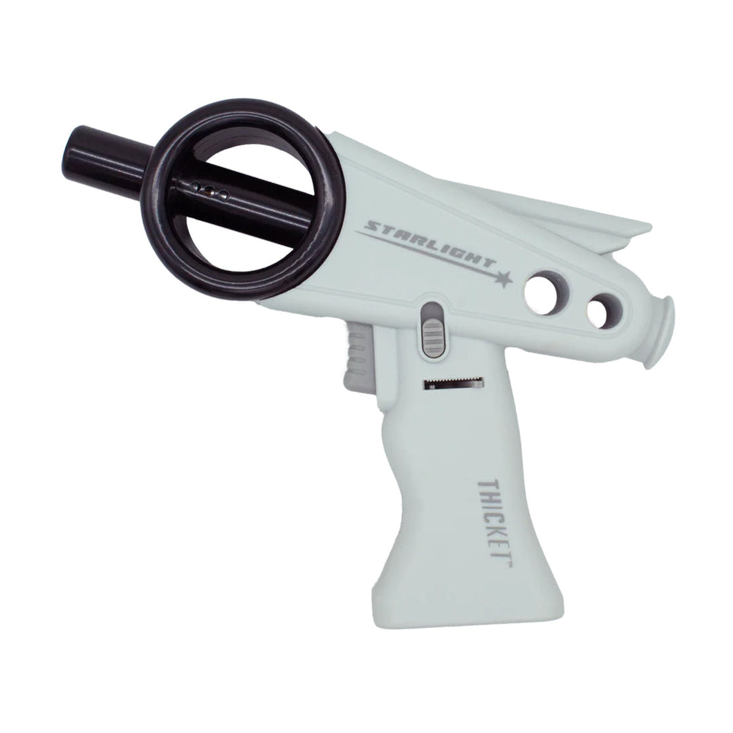 The Thicket Starlight Torch is a white and black ray gun toy with a retro-futuristic design, circular barrel detail, and rear fin, labeled 