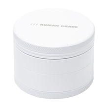 The Human Grade Grinder 4C (2.5") is a white, cylindrical aluminum herb grinder with a textured grip and "HUMAN GRADE" printed in silver uppercase letters on the lid.
