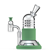 The Softglass Tandem Rig Kit is a modern water pipe made from borosilicate glass with a green platinum-cured silicone base and grip. It features a cylindrical chamber, angled mouthpiece, and side-mounted bowl for a sleek design.