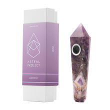 A purple amethyst Gemstone Pipe with a googly eye sits beside a white and purple "Gemstone Pipe" box featuring geometric designs—ideal for fans of unique crystal smoking pipes.