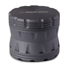 The Human Grade Grinder 2A (2.5" 4-Piece) is a matte black, cylindrical aluminum grinder with ridged grooves, a pollen screen, and “HUMAN GRADE” engraved on the top.