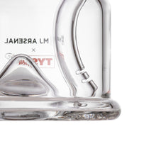 Close-up of the bottom section of the MJ Arsenal x Tyson 2.0 Punch-Out bubbler, featuring a curved handle and part of a triangular structure inside, with "ML ARSENAL" and "TY" faintly visible in reverse on the glass.