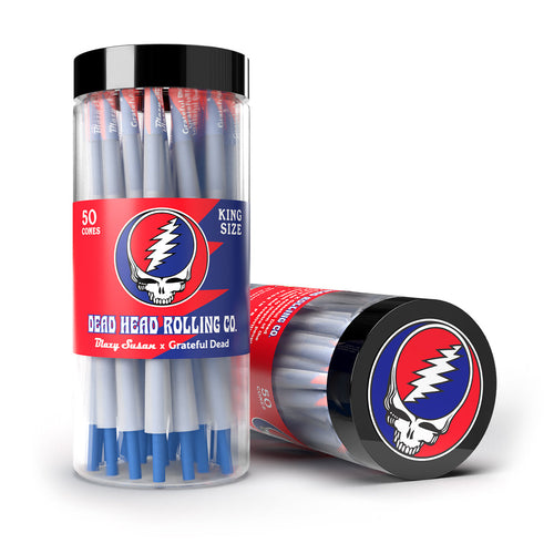 A clear container labeled Blazy Susan x Grateful Dead Cones, featuring the iconic skull logo, holds 50 king size pre-rolled cones. Two cones display the colorful Grateful Dead branding—one upright, one on its side.
