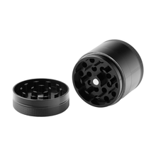 The BIGFUN! Medium Grinder, shown with its lid off to display sharp teeth and pollen sift feature, has a sleek black aluminum design. Both grinder and lid rest on a white background for a modern look.