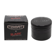 A black Hammercraft x RAW 2.2" Grinder is displayed beside its branded box, which includes white and red product details. The metallic grinder is cylindrical with a textured top.