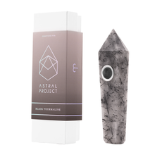 The Gemstone Pipe is a black tourmaline crystal smoking pipe with a circular, replaceable mesh bowl and pointed faceted shape. It displays striking black streaks and comes in an Astral Project-labeled box.