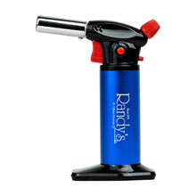 Randy’s Torch is a blue and black butane torch with a red ignition button, ergonomic design, flame control knob, branded “Randys” on the side, and stands upright on a flat base.
