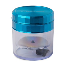 The Human Grade Storage Grinder 1A (2.5") is a small, metallic blue 4-piece aluminum grinder with a faceted, shiny top and printed text, transparent lower chamber showing its teeth and grinding plate, plus a built-in pollen screen.