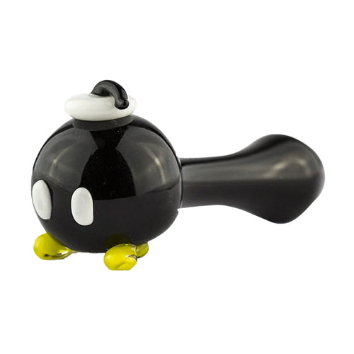 The Empire Glass Works Bomber Dry Pipe is a handcrafted spoon pipe shaped like a black cartoon bomb with white eyes, yellow feet, and a white wick tip, inspired by the iconic Bob-omb character from video games.