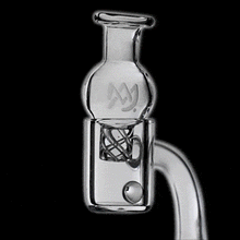 A clear carb cap with a spinning ball is placed on a quartz banger, making two MJ Arsenal Quartz Terp Pearls (6mm) spin rapidly. The solid black background highlights the dabbing accessories and their mesmerizing motion.