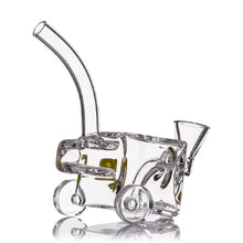 The MJ Arsenal Woodchipper Blunt Bubbler is a clear glass piece shaped like a small cart with four wheels, a curved neck, and a funnel-like opening, designed for creative smoking with enhanced water filtration.
