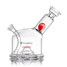 The MJ Arsenal x Tyson 2.0 Punch-Out is a clear borosilicate glass bubbler with red detail, MJ Arsenal and Tyson 2.0 logos, a round base, and an angled neck for smooth sessions.