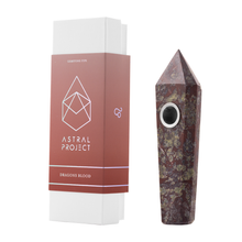 A Gemstone Pipe with a pointed crystal design and replaceable mesh bowl stands upright beside its box, labeled Astral Project and Dragons Blood, with a geometric logo on a red background.