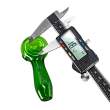 A digital caliper measures the diameter of the Grav Sandblasted Spoon, made of green glass with a matte finish and "GRAV" engraved, showing a reading of 18.42 on its screen.