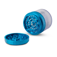 The Human Grade Storage Grinder 1A (2.5") is a blue transparent aluminum 4-piece grinder with a pollen screen, shown open with the lid beside the body on a white background, revealing its sharp metal teeth inside.