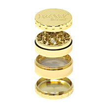 The RAW Ethereal Grinder, shown disassembled with its four gold-plated parts—lid, grinding section, mesh screen, and collection chamber—features an engraved RAW logo on the lid for an elevated grinding experience.