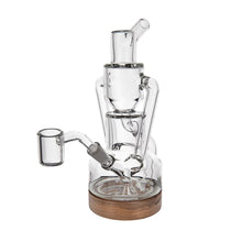 The MJ Arsenal Alpine Series - Apex Mini Rig is a clear glass water pipe with multiple chambers, a wooden base, a side attachment, and intricate internal glasswork for smooth smoking or vaporizing, inspired by the double uptake recycler design.