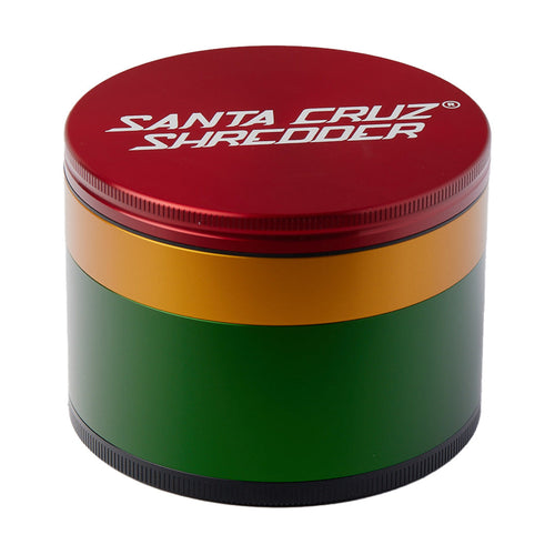 The Santa Cruz Shredder Large 4-Piece Grinder is a round anodized aluminum grinder with a red lid, labeled Santa Cruz Shredder, and features gold, green, and black bands around its body.