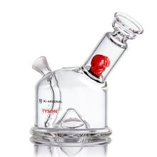 The MJ Arsenal x Tyson 2.0 Punch-Out is a clear borosilicate glass bubbler with a tilted mouthpiece, red boxing glove inside, branded accents, a round base, and built-in downstem—all showcased against a white background.