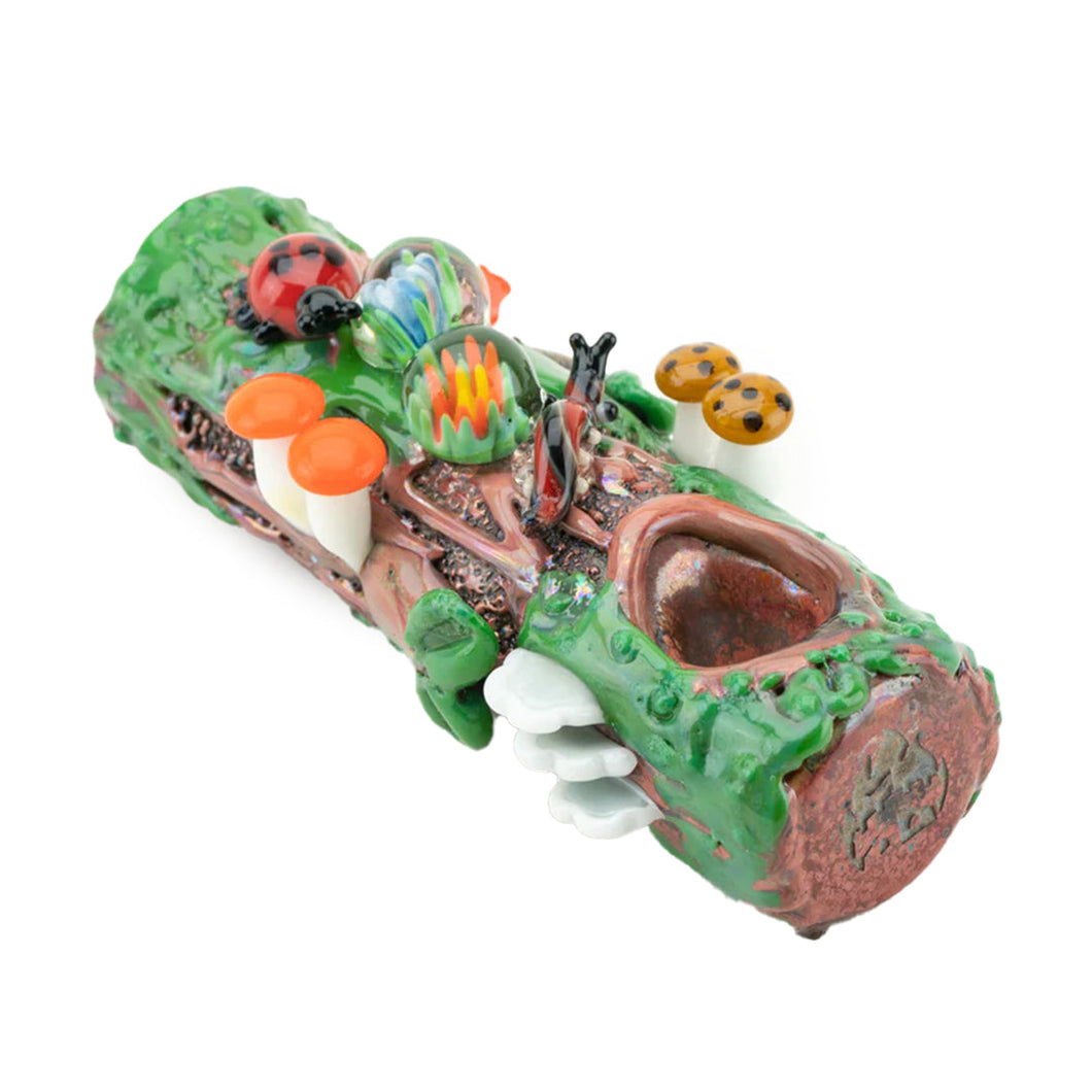 The Empire Glass Works Mossy Log Dry Pipe is a colorful, hand-crafted borosilicate piece shaped like a log and adorned with green moss, mushrooms, a snail, and a ladybug, creating a whimsical forest-themed design.