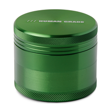 A metallic green Human Grade Grinder 1A (2" 4-piece) aluminum grinder with a screw-on lid and "HUMAN GRADE" printed on the top.