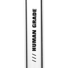 A close-up of a shiny metallic Human Grade Downstems surface with bold black HUMAN GRADE text printed vertically and three diagonal lines below—resembling a premium 14mm water pipe replacement.