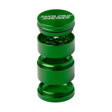 A green Santa Cruz Shredder Medium 4-Piece Grinder is shown disassembled with its lid, grinding section, collection chamber, and bottom compartment stacked vertically.