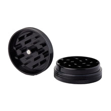 The 2 Piece Flat Grinder is shown in black metal. One grinder is open, revealing sharp, diamond-shaped teeth, with the other half beside it. Available in various colors and size options. Background is white.
