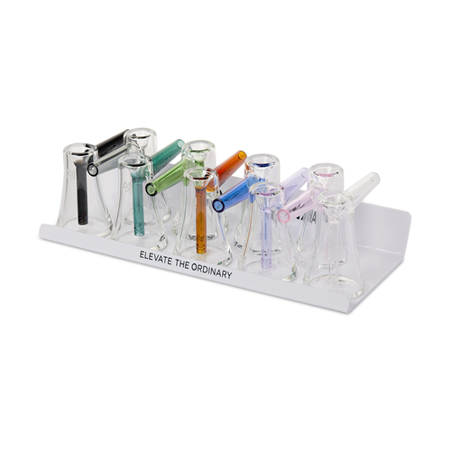 The MJ Arsenal Bubbler Bundle includes eight glass smoking pipes with colorful, unique mouthpieces. Inspired by Fulcrum Bubblers, they are displayed in a white tray labeled ELEVATE THE ORDINARY.