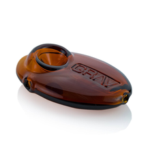 The Grav Pebble Spoon is a brown, oval hand pipe with the brand name embossed on top, a bowl at one end, and a mouthpiece at the other—perfect for discreet, portable use against any white background.