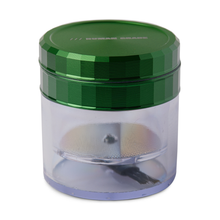 The Human Grade Storage Grinder 1A (2.5") is a green and clear 4-piece grinder with a metallic green lid and an internal pollen screen, ideal for herbs or spices, shown on a white background.