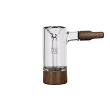 The MJ Arsenal Alpine Series - Steamboat Bubbler is a clear borosilicate glass smoking pipe with a wooden mouthpiece and base, a minimalist design, and a small engraved logo—a refined tribute to classic MJ Arsenal craftsmanship.