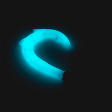 The Empire Glassworks Dab Tool, shaped like a glowing blue dolphin and crafted from borosilicate glass, stands out brilliantly against a dark background, highlighting the graceful curve of the dolphin’s body.