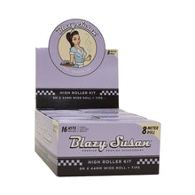A display box of Blazy Susan Purple Rolling Papers features a cartoon woman logo, purple packaging with “8 meter roll,” contains 16 kits per box, and includes deluxe rolling accessories and purple papers for smoking.