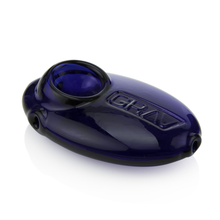 The Grav Pebble Spoon is a discreet, oval-shaped hand pipe in dark blue with GRAV embossed on top. It features a bowl at one end, mouthpiece at the other, and a sleek, glossy finish.