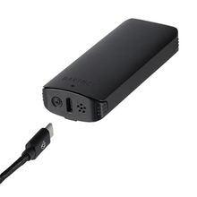 A black Davinci ARTIQ 510 Thread Battery Vape with an elongated air path, USB-C charging port, power button, and ventilation holes is shown next to a detached USB-C charging cable.