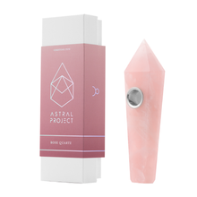 The Gemstone Pipe, made from rose quartz and featuring a replaceable mesh bowl, stands next to its pink and white box labeled “Astral Project Gemstone Pipe – Rose Quartz,” delivering a premium crystal smoking experience.